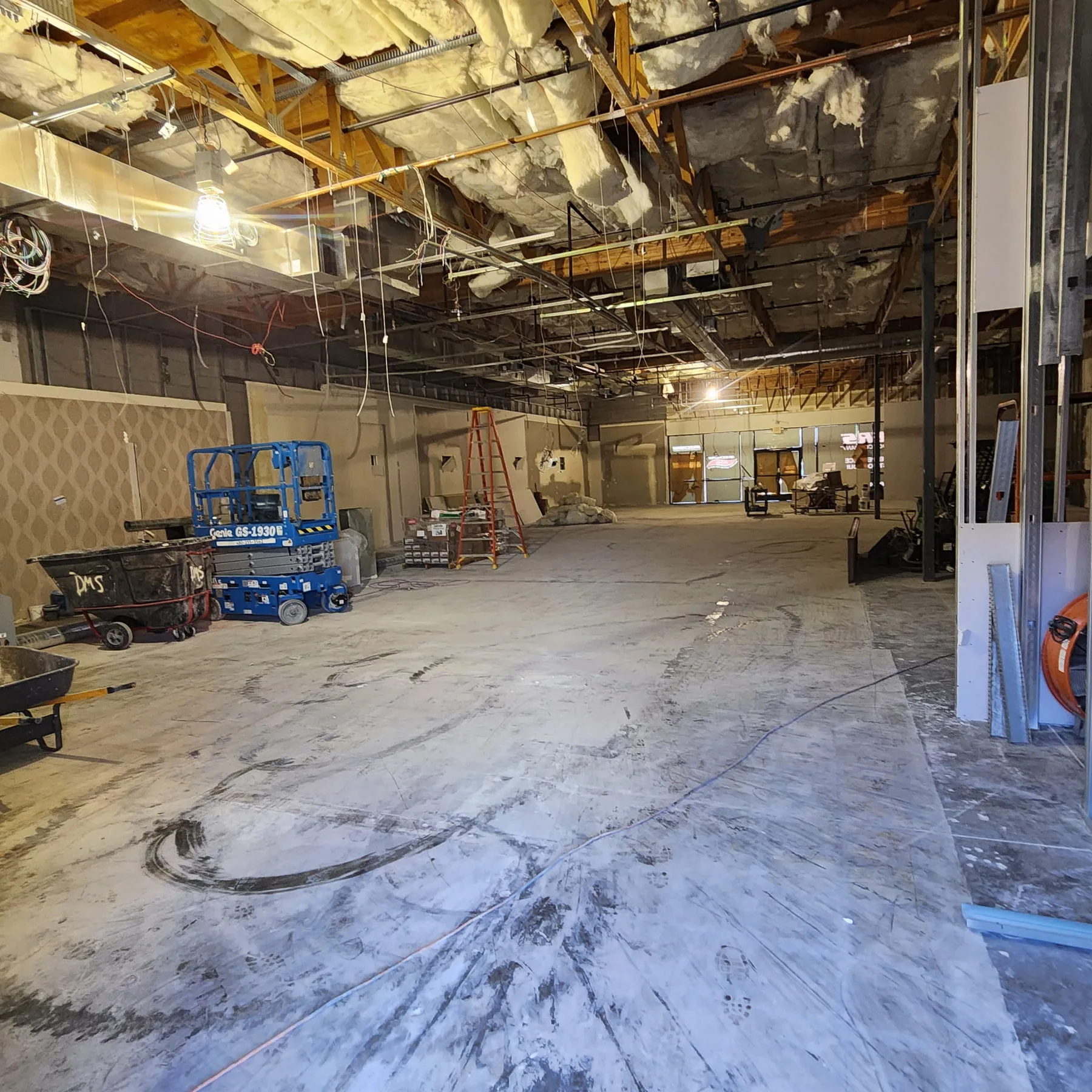 Open commercial space mid-demolition with scissor lifts and exposed ceiling